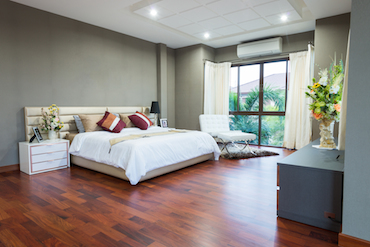 a large room with a hardwood floor tall window overlooking trees 